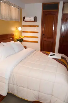 a bedroom with a large white bed and a door at Picos House MachuPicchu in Machu Picchu