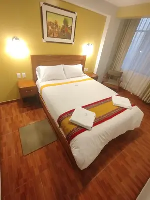 a bedroom with a large bed with white sheets at Picos House MachuPicchu in Machu Picchu
