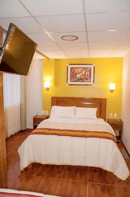 a large bed in a room with a yellow wall at Picos House MachuPicchu in Machu Picchu