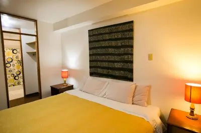 a bedroom with a bed with two lamps and a mirror at Casa de Baraybar in Lima