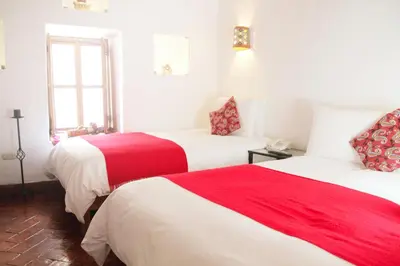 two beds in a room with red and white sheets at Rumi Wasi in Cusco