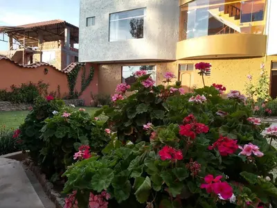a house with pink flowers in front of it at Hotel Chinchero Boutique & Tours in Chinchero