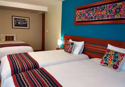 a hotel room with two beds and a blue wall at Hotel Chinchero Boutique & Tours in Chinchero