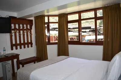 a bedroom with a white bed and two windows at Casa De Luz Hotel in Machu Picchu