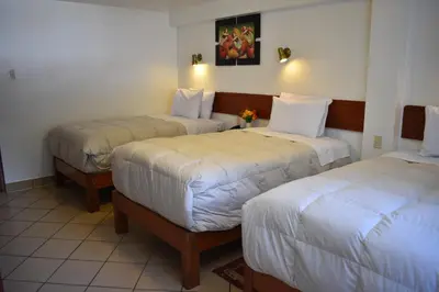 a hotel room with two beds with white sheets at Casa De Luz Hotel in Machu Picchu