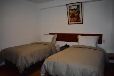 a hotel room with two beds and a picture on the wall at Casa De Luz Hotel in Machu Picchu