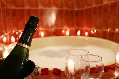 a bottle of champagne and two glasses on a table with a bath tub at Hotel Bohemia in Lima