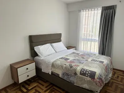 a bedroom with a bed with a quilt and a window at VIVE Apartments Cusco in Cusco