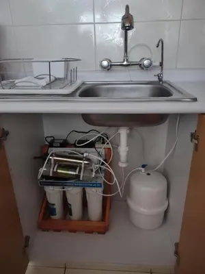 a sink under a kitchen counter with buckets under it at VIVE Apartments Cusco in Cusco