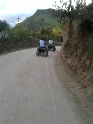 two people riding motorcycles down a dirt road at Suzet House in Oxapampa