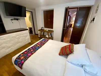a bedroom with a white bed with pillows and a television at Cusco Hotel Boutique in Cusco