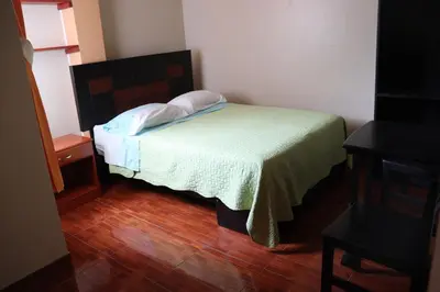 a small bedroom with a bed with a green blanket at Gran Hotel Virrey in San Ramón
