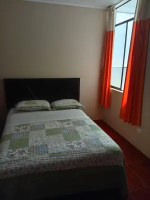 a bedroom with a bed with a quilt and two windows at Gran Hotel Virrey in San Ramón