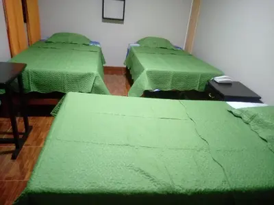 three beds in a room with green covers at Gran Hotel Virrey in San Ramón
