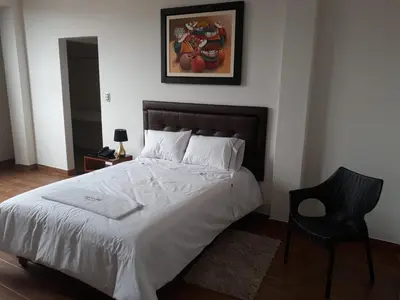 a bedroom with a large bed and a chair at Gran Caral Hotel in Barranca