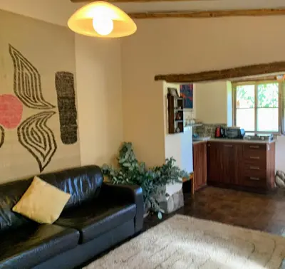 a living room with a black leather couch and a kitchen at Bungalows Perayoc in Urubamba