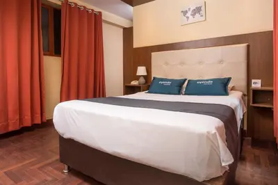a bedroom with a large bed with blue pillows at Ayenda Posada Inn in Cusco