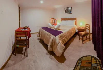 a bedroom with a bed and a table and a chair at Askha Cusco in Cusco