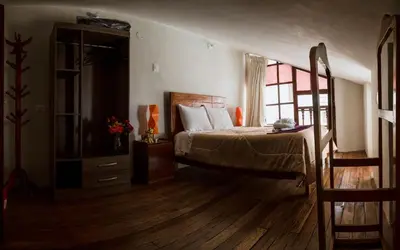 a bedroom with a bed and a dresser and a window at Askha Cusco in Cusco
