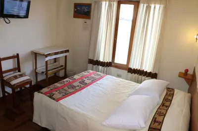 a bedroom with a bed and a window and a table at Picol Hostal in Cusco