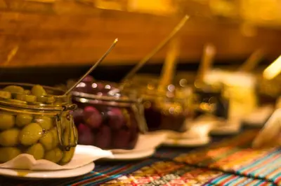 a table with plates of fruit and a jar of pickles at Gringo Bill's Boutique Hotel in Machu Picchu