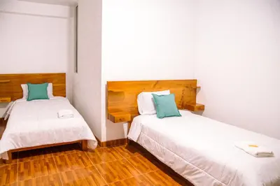 two beds in a small room with wooden floors at La Posada D'Benjamín in Oxapampa