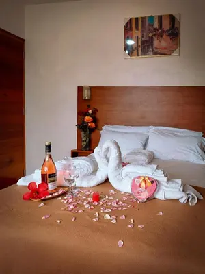 a bed with a swan towel and a bottle of wine at La Posada D'Benjamín in Oxapampa