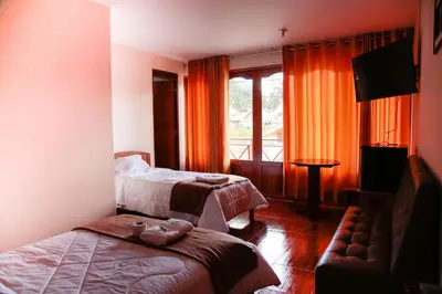 a hotel room with two beds and a television at La Posada D'Benjamín in Oxapampa
