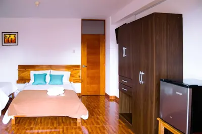 a bedroom with a bed with blue pillows and a television at La Posada D'Benjamín in Oxapampa