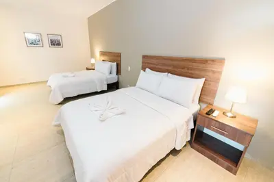 a hotel room with two beds with white sheets at Villa Oasis in Ica
