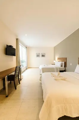 a hotel room with two beds and a desk at Villa Oasis in Ica