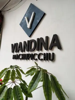 a sign on a wall with a plant at Viandina Machupicchu in Machu Picchu