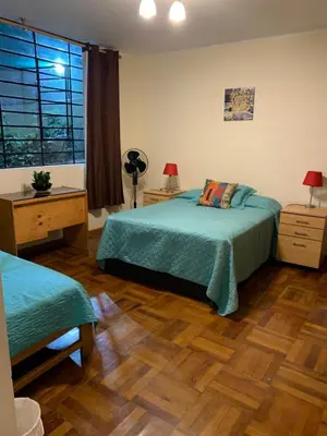 a bedroom with two beds and a wooden floor at Uli´s house in Lima