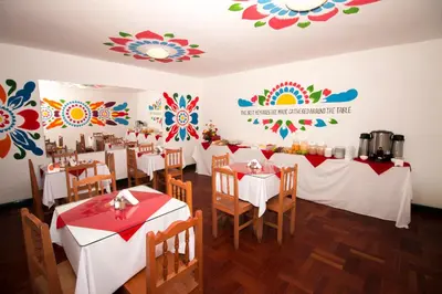 a restaurant with white tables and chairs and flowers on the walls at Cusco Plaza Nazarenas in Cusco