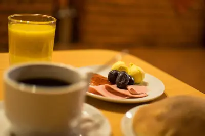 a table with a plate of food and a cup of coffee at Cusco Plaza Nazarenas in Cusco