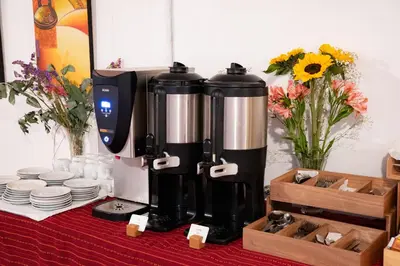 a coffee maker on a table with plates and flowers at Hotel Cusco Plaza Saphi in Cusco