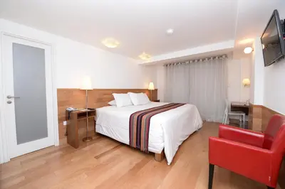 a hotel room with a bed and a red chair at Hotel Plaza de Armas Cusco in Cusco