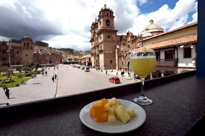 a plate of food and a glass of wine on a table at Hotel Plaza de Armas Cusco in Cusco