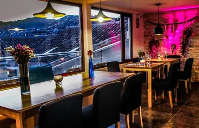 a restaurant with wooden tables and chairs and a window at Tariq Boutique in Cusco