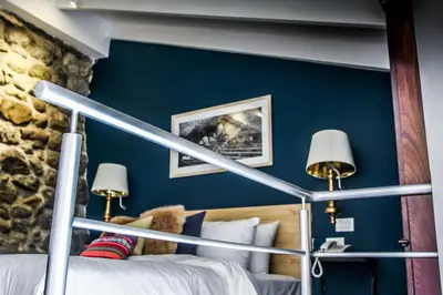 a bedroom with a blue wall with a bed and two lamps at Tariq Boutique in Cusco