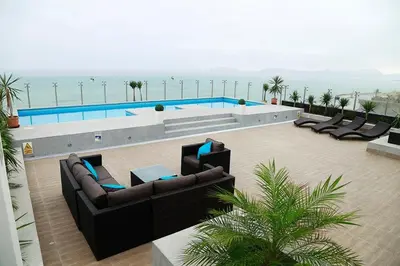 a swimming pool with couches and chairs next to the ocean at Lima Flats in Lima