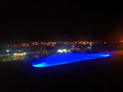 a swimming pool at night with a city in the background at HASSINGER RANCH Cabañas in Oxapampa