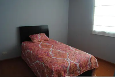 a bedroom with a bed with a comforter and a pillow at Beachfront Condo San Miguel in Lima