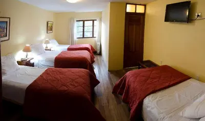 a hotel room with three beds and a television at Centro Vacacional Huaychulo in Concepción