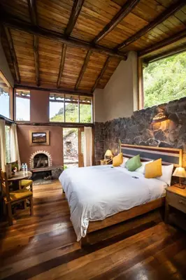 a bedroom with a large bed and a stone wall at Sacred Dreams Lodge in Urubamba