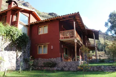 a red house with a porch and a balcony at Sacred Dreams Lodge in Urubamba