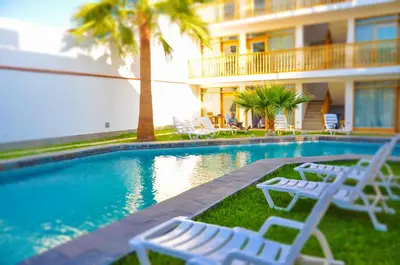 a swimming pool with white lounge chairs next to a building at Hotel Boutique La Angostura in Ica