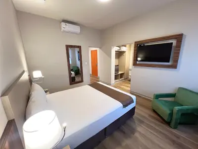a hotel room with a bed and a green chair at DM Hoteles Nasca in Nazca