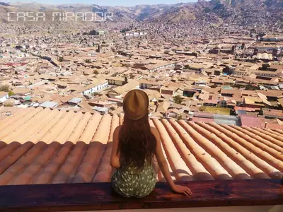 a girl sitting on a roof looking at a city at Casa Mirador guesthouse in Cusco