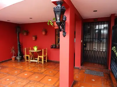 a room with a red wall with a table and a door at Hospedaje La Videna in Lima